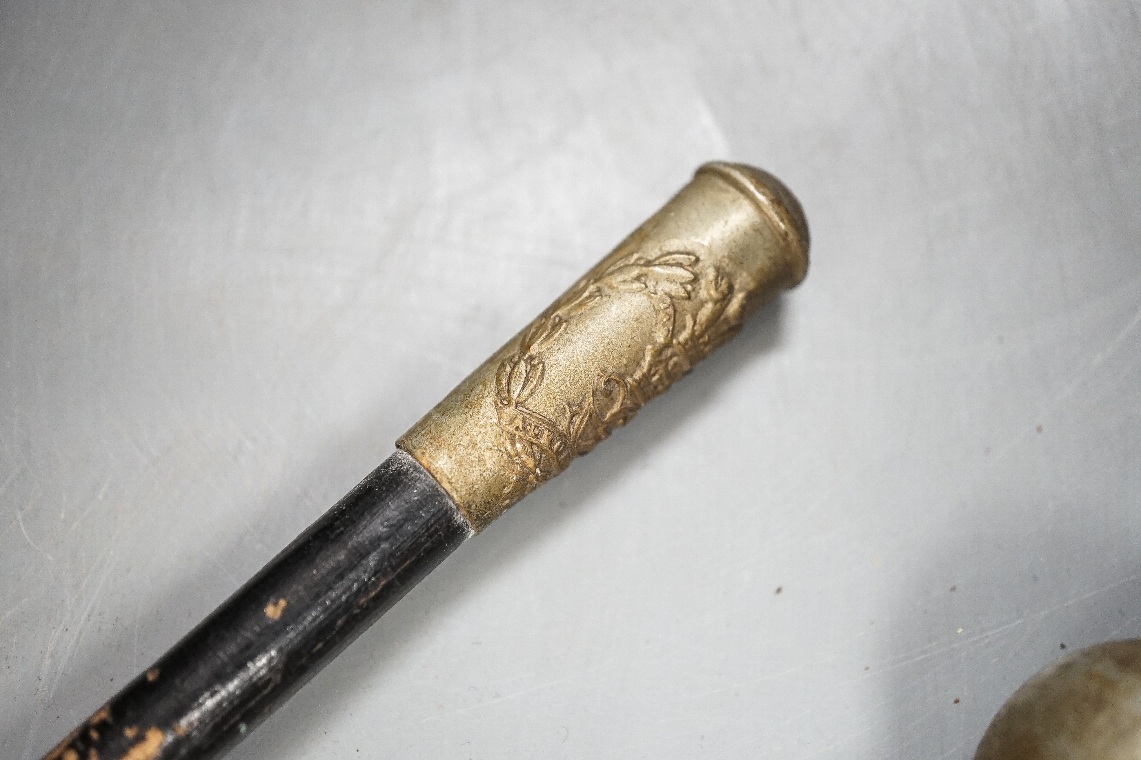 A group of WWI and WWII militaria badges, buttons, two swagger sticks, an armband and a World War I German POW inscribed plaster ornament, longest swagger stick 70 cms long.